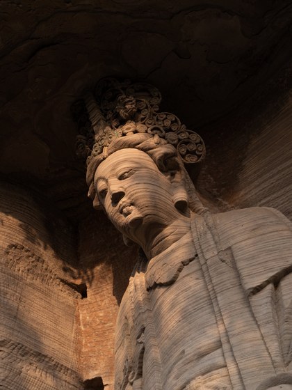 Stone bodhisattva sculpture, wider view in warm light